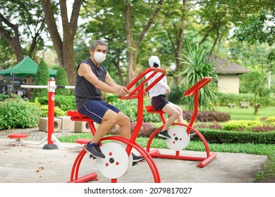 An Old Man With Protective Facemask Doing Exercise At Outdoor Fitness Equipment In The Park, Concept Health Care In Elderly People, Lifestyle 