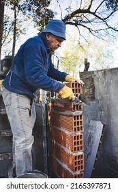 Old Man Raising Wall And Gluing Brick With Trowel