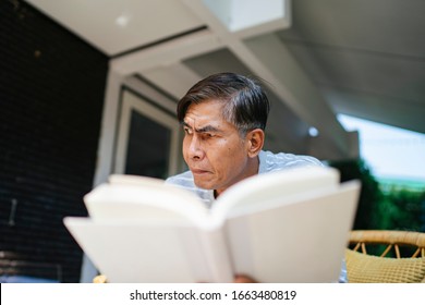 Old Man Reading The Book And Thinking About The Plot In The Yard.