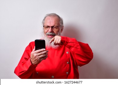 Old Man In A Red Bib Shirt Is Not Happy With What He Sees On The Phone.
Elderly, Retired Gentleman Is Annoyed With His Cellphone.   

Old Man Reading Disturbing News On His Smartphone
