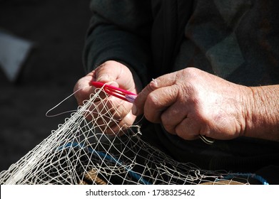 old man is repairing fishing net with hands. - Powered by Shutterstock