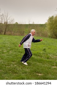 Old Man In Seventies Jogging In Park