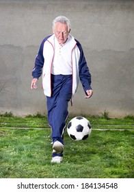 Old Man In Seventies Kicking A Soccer Ball In Courtyard