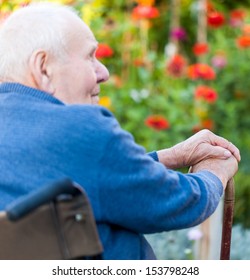 Old Man Sitting Alone In A Wheelchair Out In The Garden.