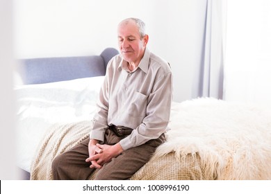 The old man sitting on a bed in the room at home