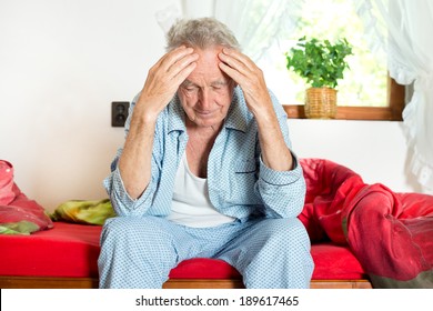 Old Man Sitting On Bed And Holding Head With Hands