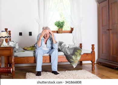 Old Man Sitting On Bed And Holding Head With Hands