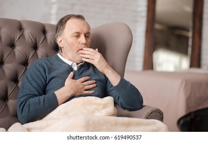 Old Man Sitting On Couch And Coughing