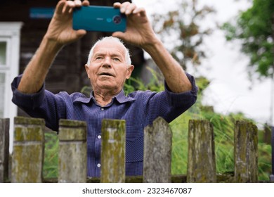 Old man with smartphone taking photographs outdoors - Powered by Shutterstock