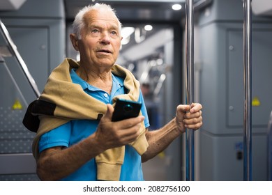 Old Man Standing Inside Subway Car With Phone In Hand.