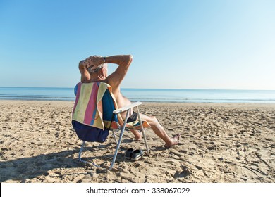 Old Man Sunbathing At The Beach