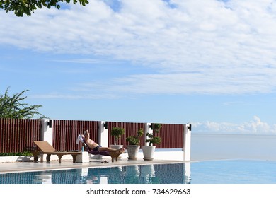 The Old Man Is Sunbathing Side The Pool And The Sea.