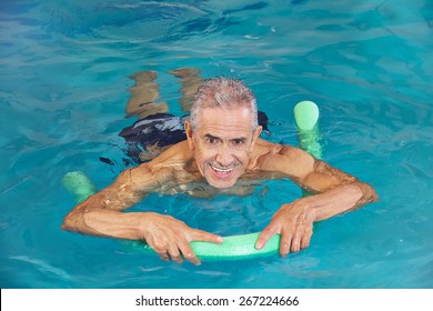 Old Man Swimming In Water Of Hotel Pool With Swim Noodle