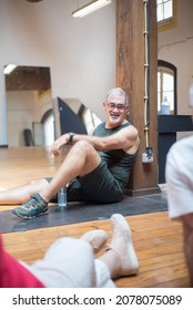 Old Man Taking Break After Dance Class. Smiling Male Pensioner Sitting On Floor With Water Bottle. Dance, Hobby, Healthy Lifestyle Concept