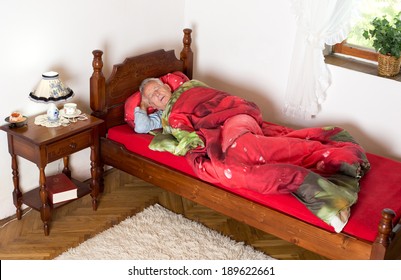 Old man taking a nap with open mouth in his bed