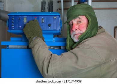 Old man with thick winter clothes and a red face turns down his gas heater. Energy prices have exploded and many people cannot afford to keep their homes warm.