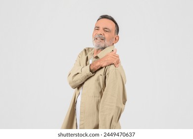 An old man touches his shoulder, showing a pained expression, isolated on a white background, got injured
