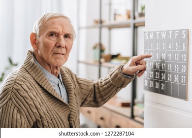 Old Man Touching Calendar Looking At Camera