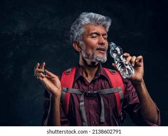 Old Man Tourist Drinking Water Against Dark Background