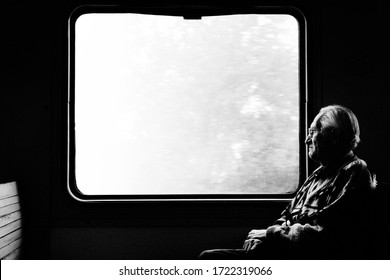 Old Man In Train. Lonely Passenger Looks Out Window. Black And White