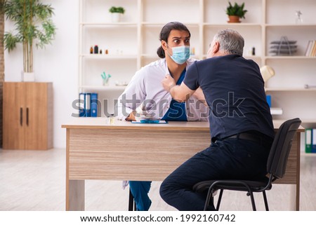 Old man visiting young doctor in covid-19 vaccination concept