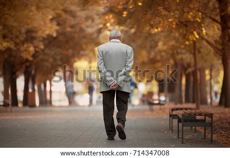 Old man walking in the autumn park.