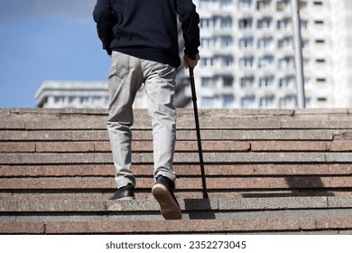 Old man with walking cane climbing stairs on city street. Concept for disability, limping adult - Powered by Shutterstock