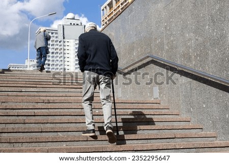 Old man with walking cane climbing stairs on city street. Concept for disability, limping adult