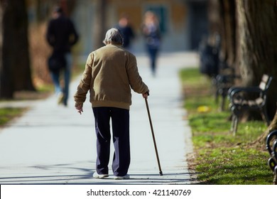 Old Man Walking Down The Street With Walking Stick