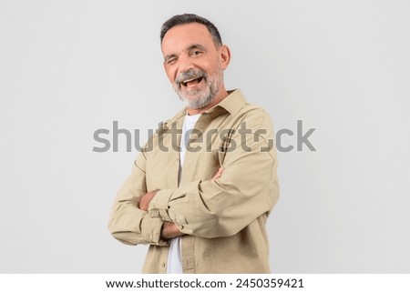 Old man with a warm smile, arms confidently crossed in front of him, isolated on a white background, exudes friendliness