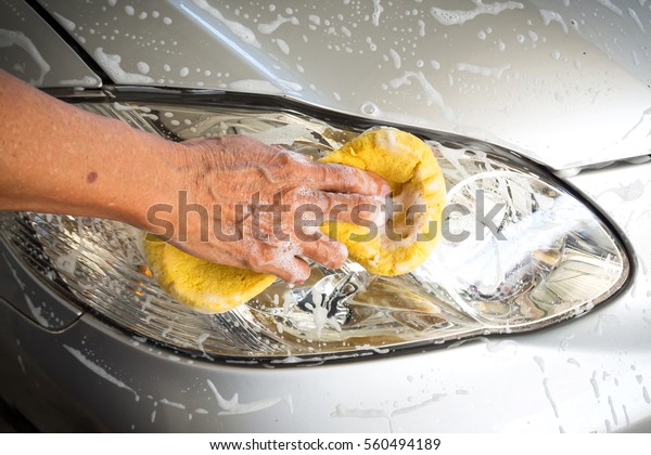 Old man washing car at home. Cleaning\
car. Closeup hand use yellow sponge washing\
car.