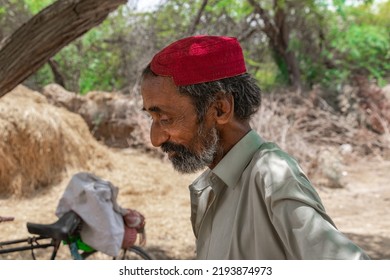 An Old Man Wearing Red Sindhi Traditional Hat And Trees In Background 