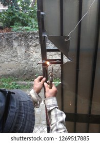 Old Man Welding A Corrosive Black Iron Handle Of Gate
