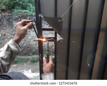 Old Man Welding A Corrosive Black Iron Handle Of Gate