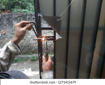 Old Man Welding A Corrosive Black Iron Handle Of Gate