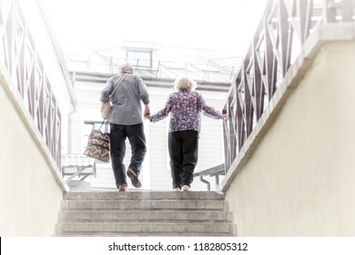 Old Man And Woman Holding Hands And Climbing The Stairs