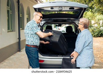 Old man and woman loading suitcase in car trunk, preparing to leave on road trip holiday. Travelling together during summer, going on vacation journey with luggage, baggage and bags. - Powered by Shutterstock