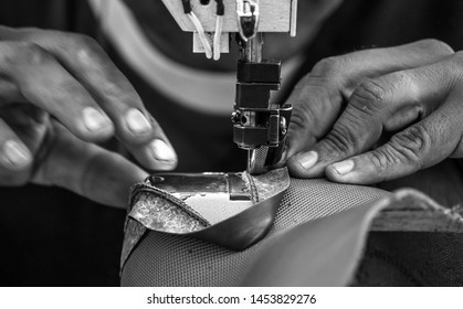 Old Man Working At A Shoe Factory With His Hands Behind His Sewing Machine (black And White Photo)