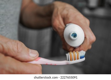 Old man with wrinkled hands squeezing paste to toothbrush close up view. Dental health care and hygiene concept. - Powered by Shutterstock