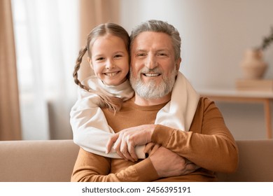 Old man and a young girl are sitting together on a couch, grandfather and granddaughter taking family picture at home - Powered by Shutterstock