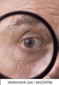 Old man's eye looking though magnifying glass