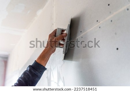 old manual worker with wall plastering tools renovating house. Plasterer renovating indoor walls and ceilings with float and plaster.