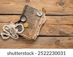 Old manuscripts with compasses, magnifier and golden pirate amulet on brown wooden background