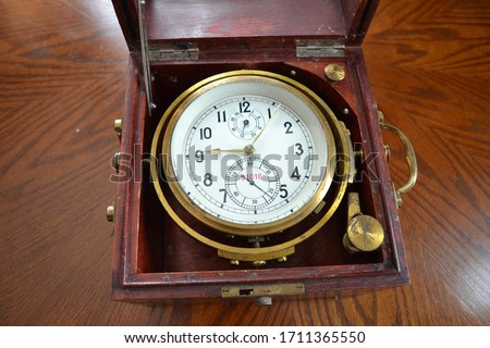 An old marine chronometer in a wooden case.