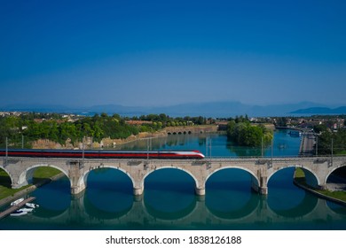 An old masonry arched viaduct carrying a train across the river valley. Blurred train movement on arch bridge over the river against the background of mountains.  - Powered by Shutterstock