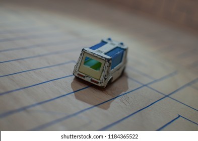 An Old Match Box Toy Car Running On A Wooden Labyrinth Pattern, Designed With A Blue Pen