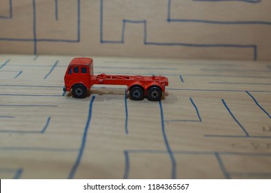 An Old Match Box Toy Car Running On A Wooden Labyrinth Pattern, Designed With A Blue Pen