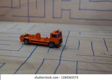 An Old Match Box Toy Car Running On A Wooden Labyrinth Pattern, Designed With A Blue Pen