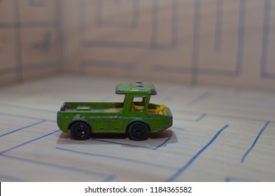 An Old Match Box Toy Car Running On A Wooden Labyrinth Pattern, Designed With A Blue Pen