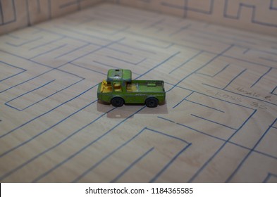 An Old Match Box Toy Car Running On A Wooden Labyrinth Pattern, Designed With A Blue Pen